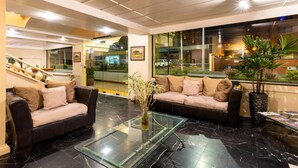 A modern lobby with two sofas, a glass coffee table, and a large window offering a view of the street. - NASS Pinar del Lago (Cuenca)