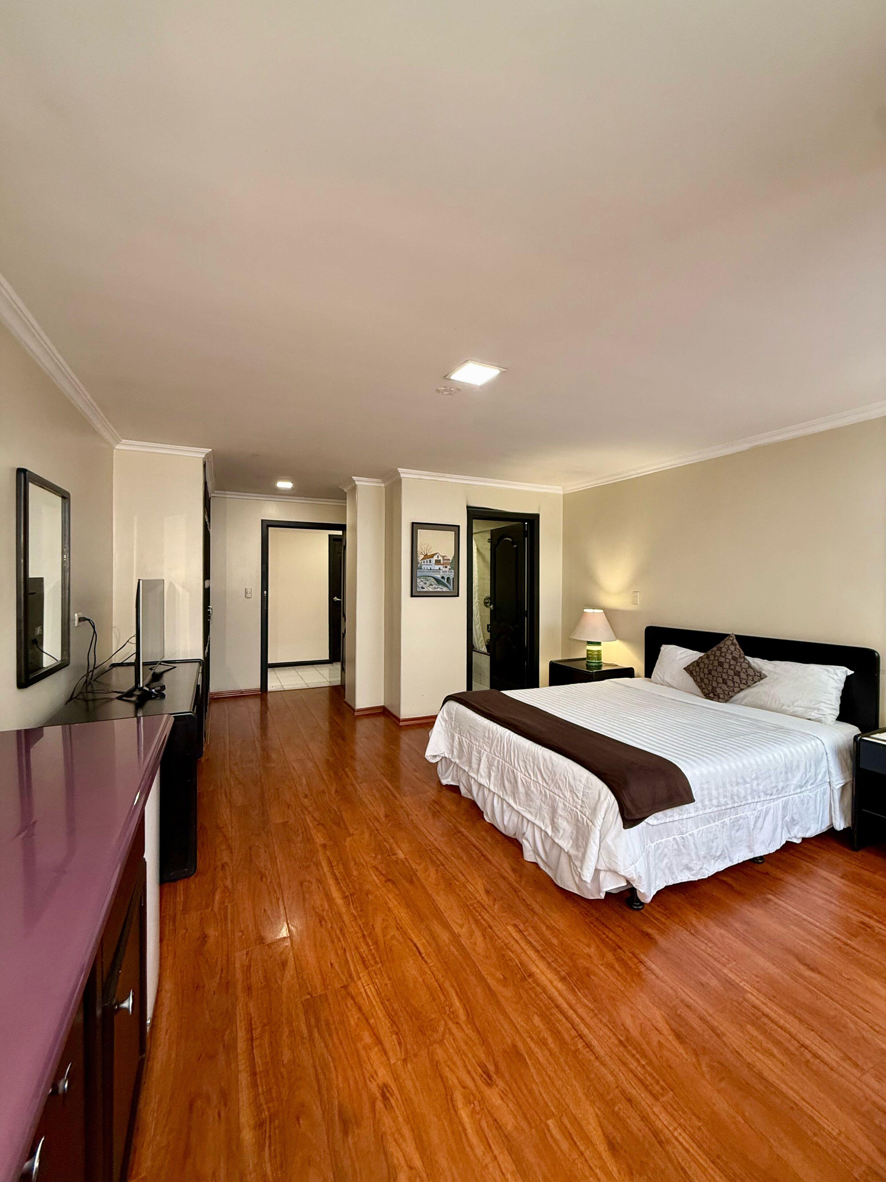 Une chambre d’hôtel comprenant un lit, une table de chevet, une lampe et un bureau avec une chaise.