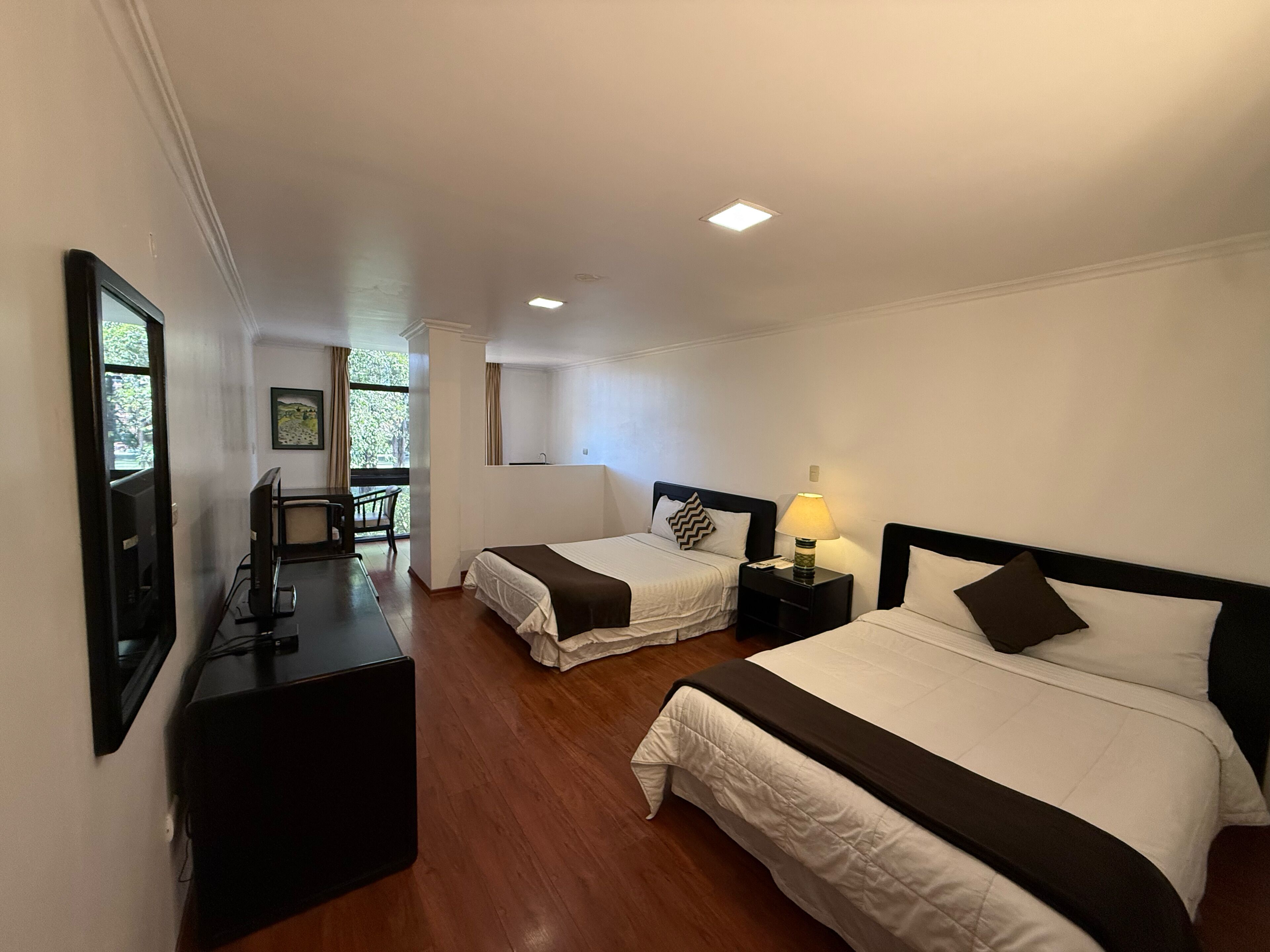Una habitación de hotel con dos camas, un escritorio, una silla y un televisor.