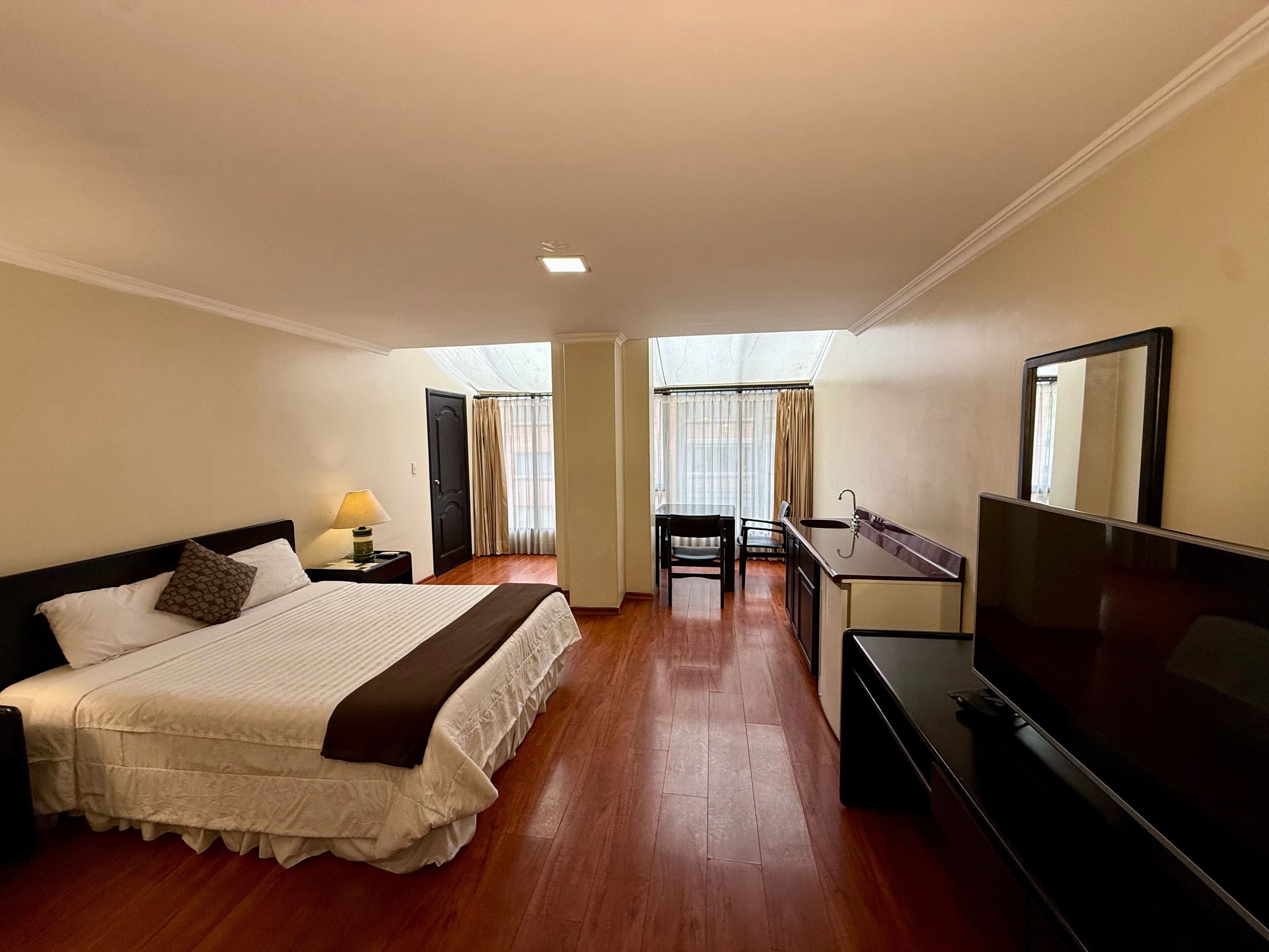 Une chambre d’hôtel équipée d’un lit, d’un bureau, d’une chaise, d’une télévision et d’une fenêtre avec des rideaux.