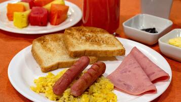 A breakfast plate with toast, sausages, scrambled eggs, and ham.