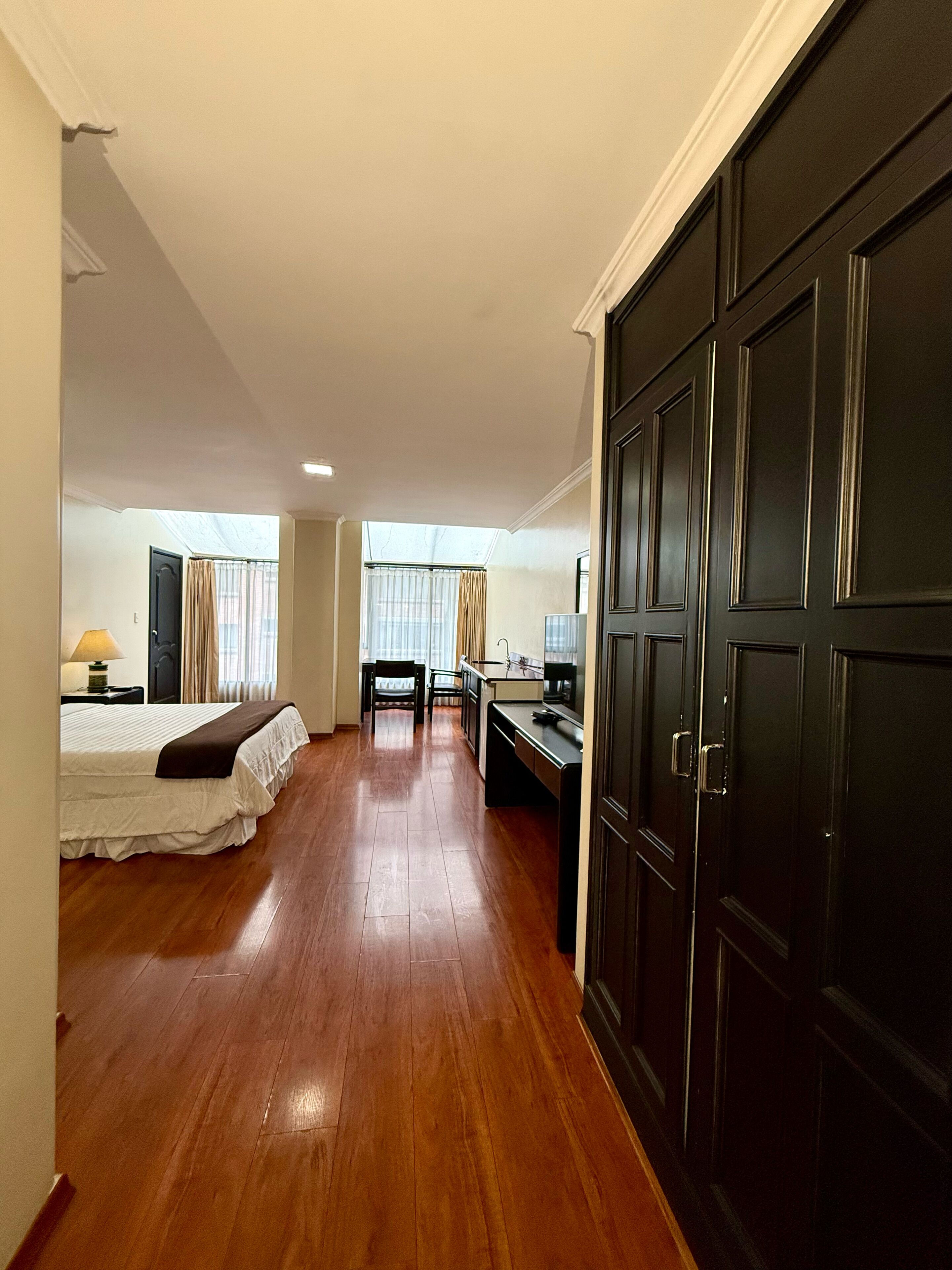 A hotel room with a bed, desk, and wardrobe.