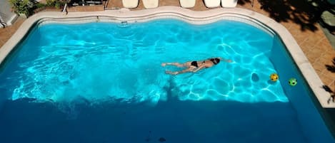 Una piscina al aire libre, sillones reclinables de piscina