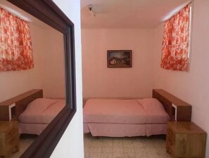 Quarto com duas camas, um quadro na parede e um espelho refletindo o ambiente.