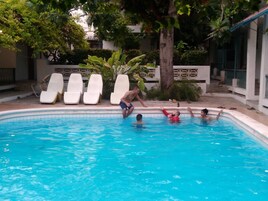 Una piscina al aire libre, sillones reclinables de piscina