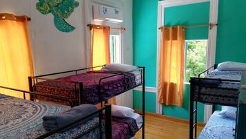 Une chambre de dortoir avec des lits superposés, une fenêtre avec des rideaux et un appareil de climatisation fixé au mur.