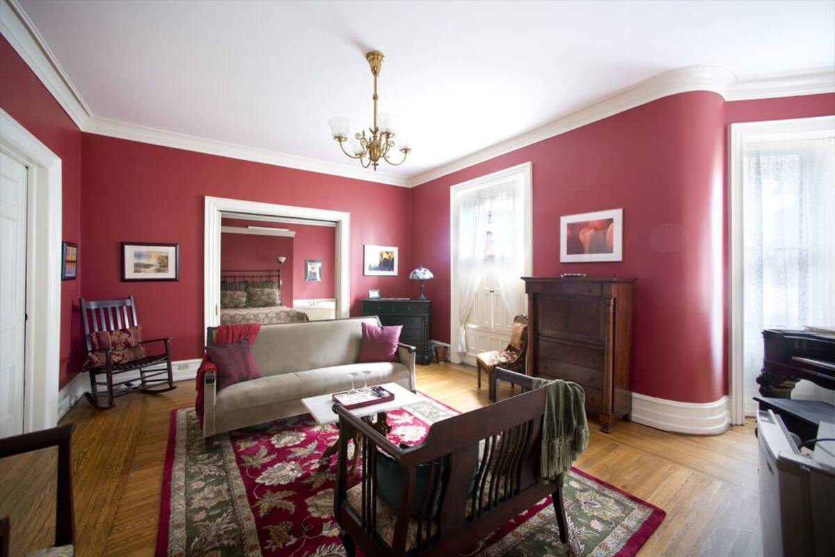 A living room with a red wall, a chandelier, a sofa, a coffee table, and a piano.