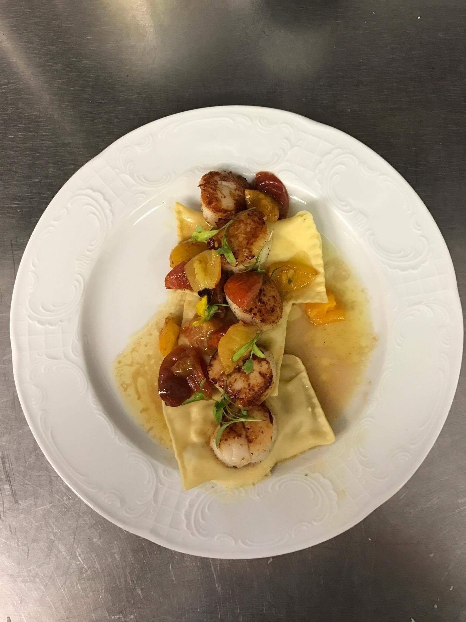 A plate of ravioli with seared scallops and caramelized onions.