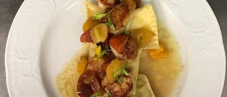 Un plato de ravioles con vieiras a la plancha y cebollas caramelizadas.