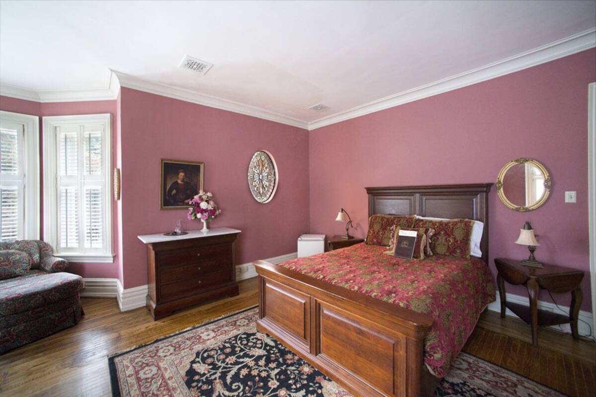 A bedroom with a large bed, dresser, and a chair.