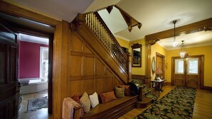 A grand staircase with a wooden handrail and a carpeted landing area. - The Peter Herdic Inn (Williamsport)