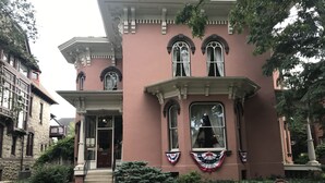 A building with a pink facade, large arched windows, and a front entrance with steps. - The Peter Herdic Inn (Williamsport)