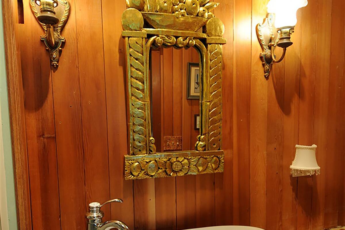 A bathroom with a wooden wall, a white sink, and two wall-mounted light fixtures.
