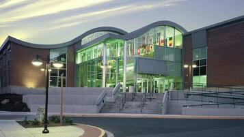 A modern building with large glass windows, a brick facade, and a set of stairs leading to the entrance.