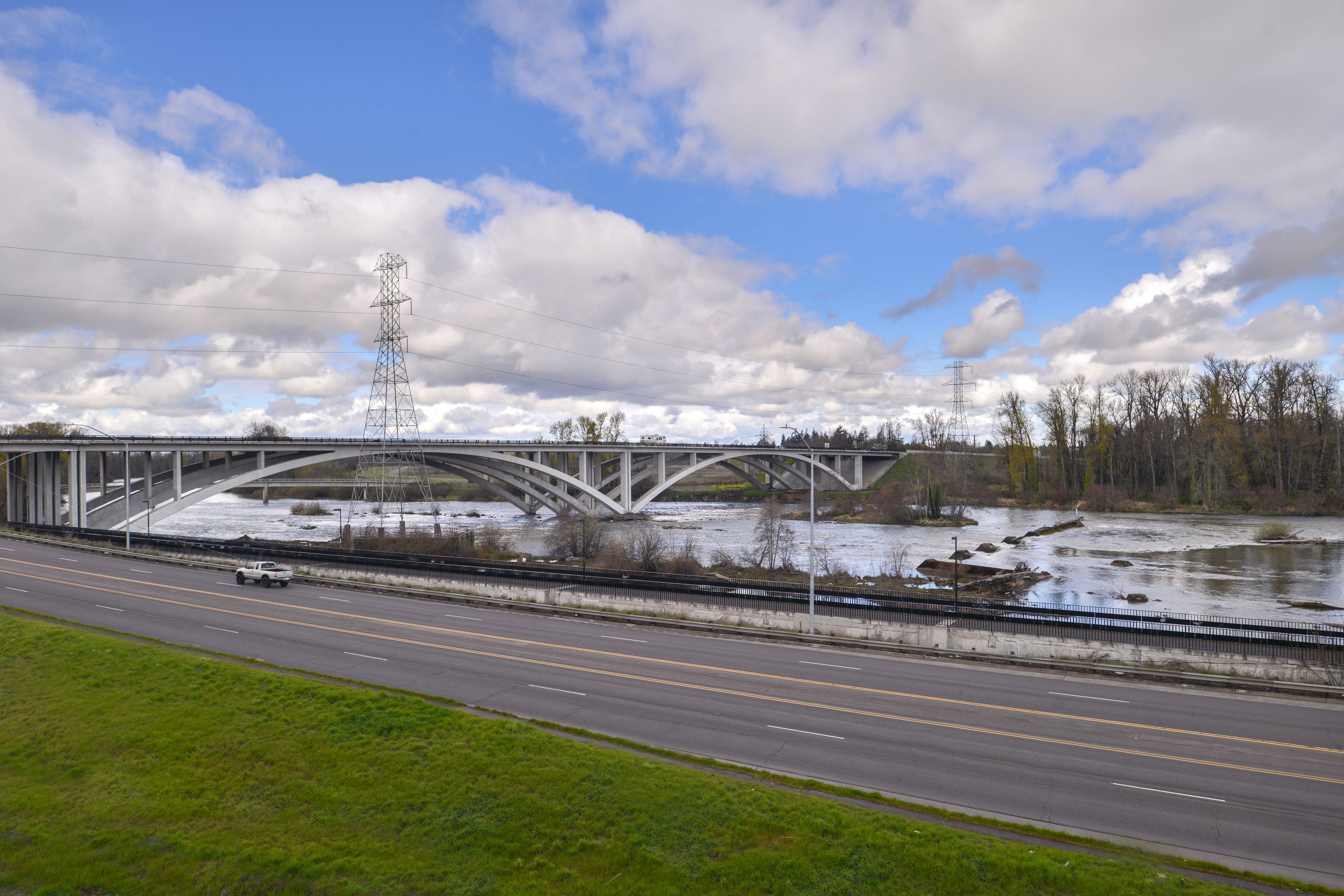 A highway bridge with a guardrail and a river below.