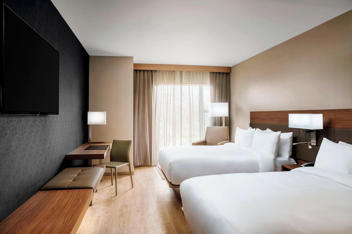 Una habitación de hotel con dos camas, un escritorio, una silla y un televisor.