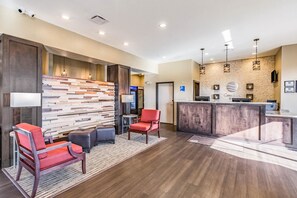 A reception area with a wooden wall, a reception desk, and seating with red chairs.