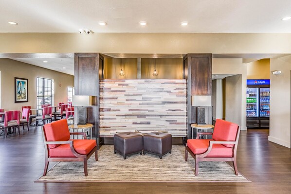 A lobby with a modern design, featuring a stone wall, red chairs, and a seating area with ottomans.