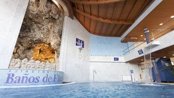 A swimming pool area with a stone wall and a sign reading "Estacion de Banos de Mil".