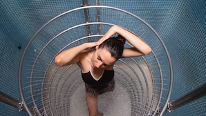 Una persona en una fuente de agua circular, posiblemente un área de spa o piscina, con barandillas metálicas y suelo de baldosas.