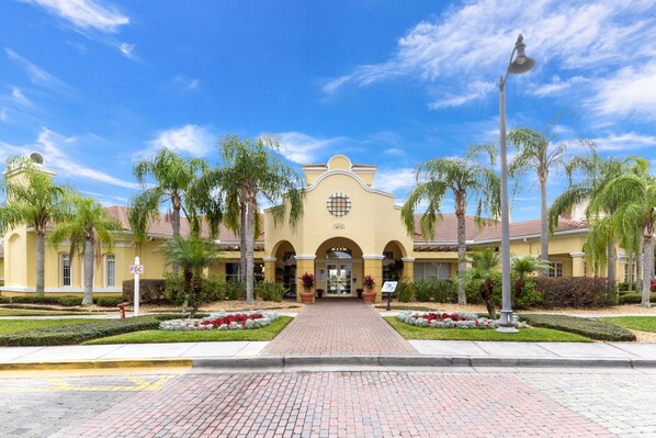 A hotel entrance with a central archway, palm trees, and a clear sky.