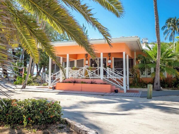 Un hotel con un espacio exterior cubierto, palmeras y cielo despejado.