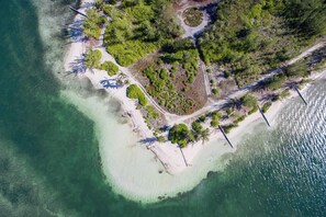Vista aérea de una isla tropical con aguas turquesas cristalinas, una playa de arena y una vegetación verde exuberante.
