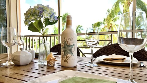 A dining table with a bottle, glasses, and a plate set for a meal.