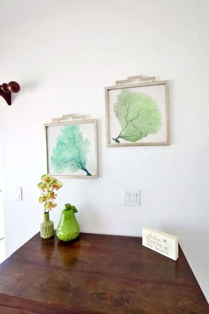 A wooden table with two framed botanical prints, a green vase with orchids, and a 'Relax... You're at the beach' sign.