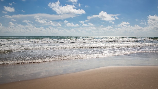 Uma praia com ondas e céu claro.