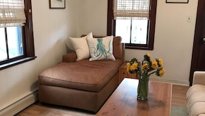 Una sala de estar con un sofá marrón, una mesa de centro de madera y un jarrón con girasoles.
