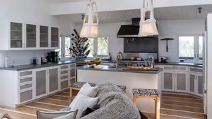 A spacious kitchen with a central island, white cabinetry, and pendant lighting.