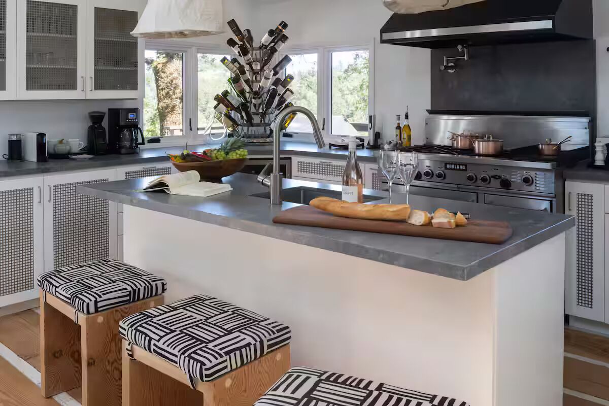 Una cocina moderna con una isla central, electrodomésticos de acero inoxidable y un ventanal amplio.