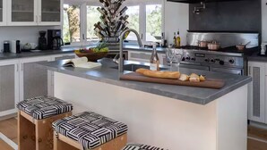 A modern kitchen with a central island, stainless steel appliances, and a large window.