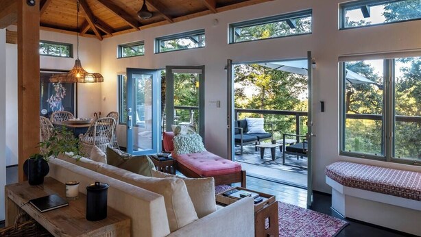 A spacious living area with a high ceiling, large windows, and a cozy seating arrangement.