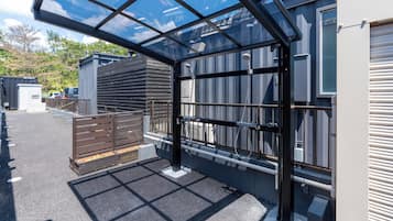 A covered parking area with a metal gate, a concrete floor, and a building with a garage door.
