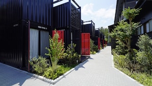 A modern building with large black shipping containers and a paved walkway. - HOTEL R9 Kujukuri (Ichinomiya)