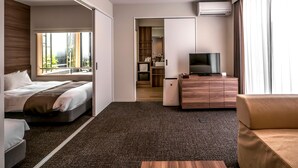 A hotel room with a bed, a sofa, a TV on a wooden cabinet, and a bathroom visible through an open door. - HOTEL R9 Kujukuri (Ichinomiya)