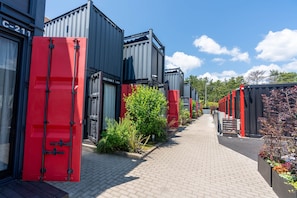 A pathway lined with shipping containers, some with red doors, and a clear sky above. - HOTEL R9 Kujukuri (Ichinomiya)