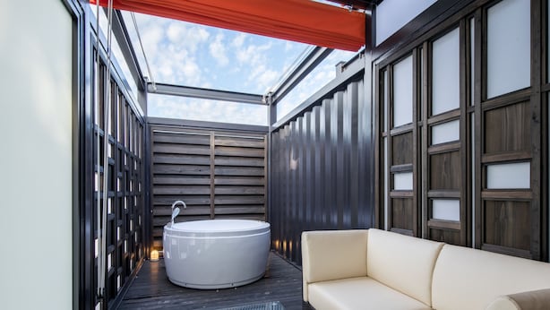 A modern outdoor bathroom with a large bathtub, a sofa, and a glass-enclosed ceiling. - HOTEL R9 Kujukuri (Ichinomiya)