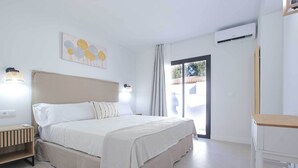 Ein modernes Schlafzimmer mit einem großen Bett, Nachttischlampen, einer Klimaanlage und Blick durch eine Schiebetür.