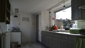 A kitchen with grey cabinets, a window, and a hanging light fixture.