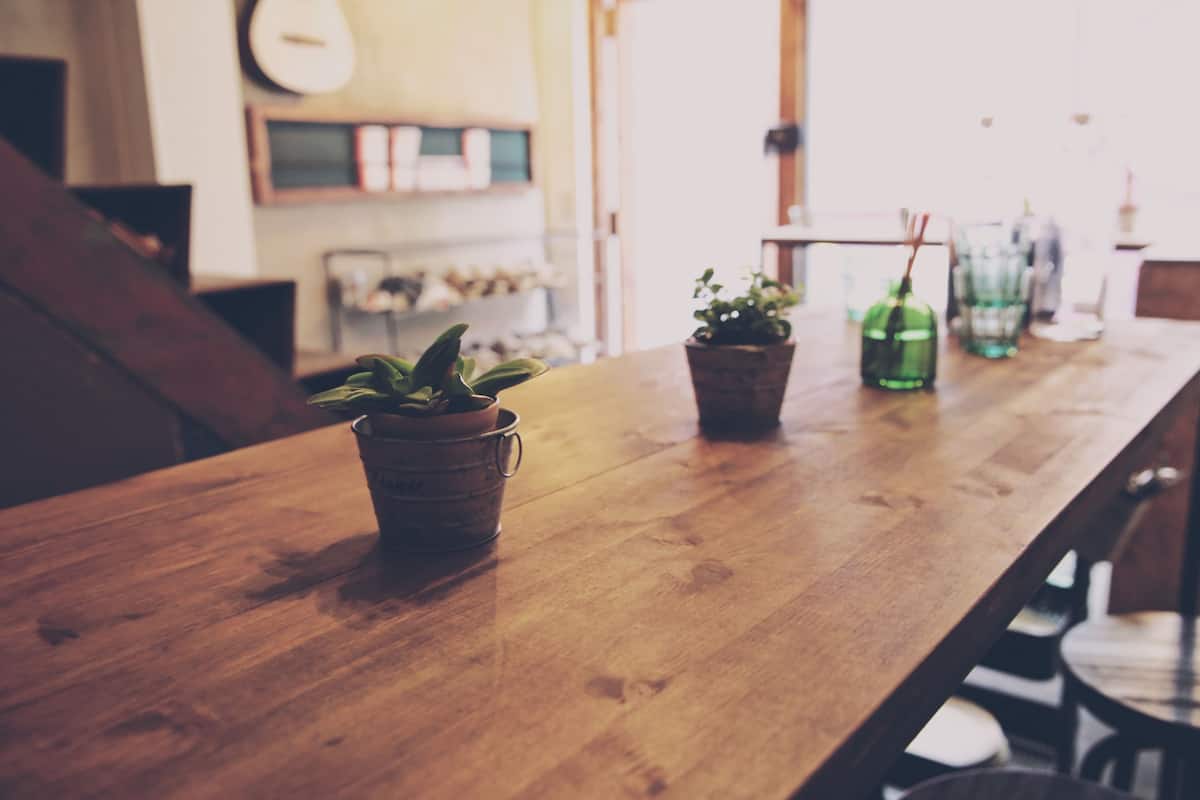 A wooden table with potted plants and a green bottle.