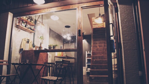 An interior space with wooden furniture, a staircase, and a brick wall. - See U Hostel Osaka (Osaka)