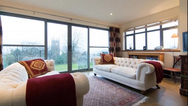 A spacious living room with large windows, a white sofa, and a fireplace.