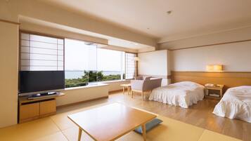 Habitación de hotel con un ventanal grande, televisor de pantalla plana, sofá, cama, mesita de noche y lámpara.