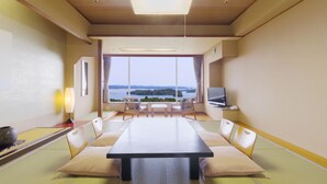 Een kamer met tatami vloeren, een lage tafel, comfortabele zitting, een televisie en uitzicht op een waterpartij.