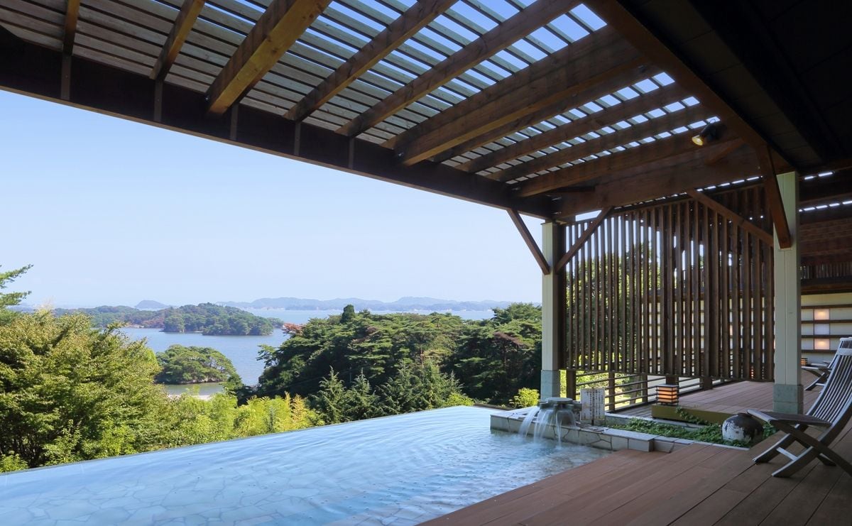Un jacuzzi con cubierta de madera y vista a un lago y montañas.
