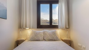 A bedroom with a bed, two bedside lamps, a window with curtains, and a view of mountains. - Nice Stay B Paz: 2 terraces with incredible views. Wifi, BBQ, swimming pool, paddle. (Panticosa)