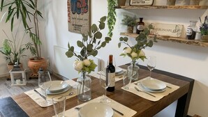 A dining table set with plates, glasses, and cutlery, surrounded by potted plants and a bottle of wine. - Beautiful old building apartment in a top location 10 minutes to town in the residential area (Biederitz)